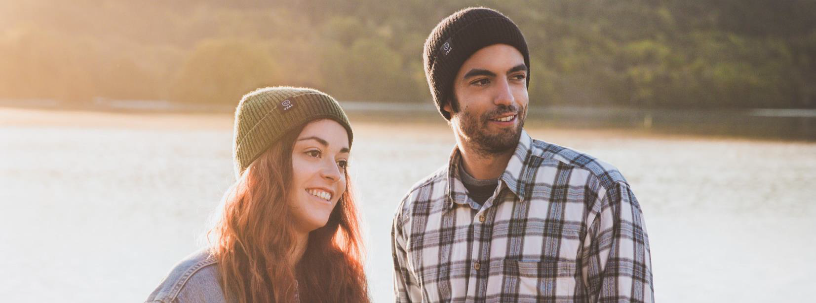 une femme et un homme devant un lac avec des bonnets en laine Ubac